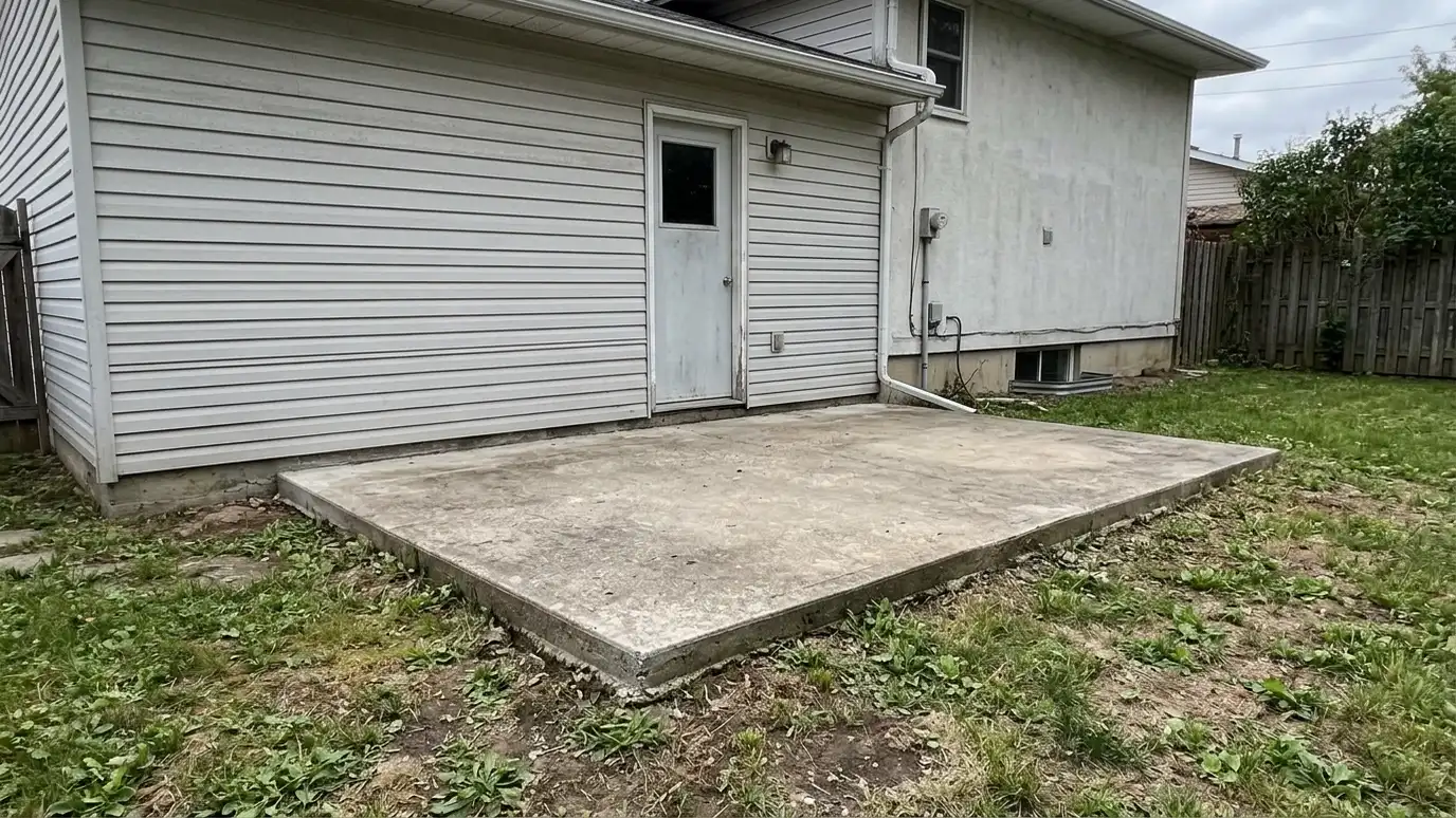Before: the back of a house with a bare concrete slab behind a plain back door with no cover or seating