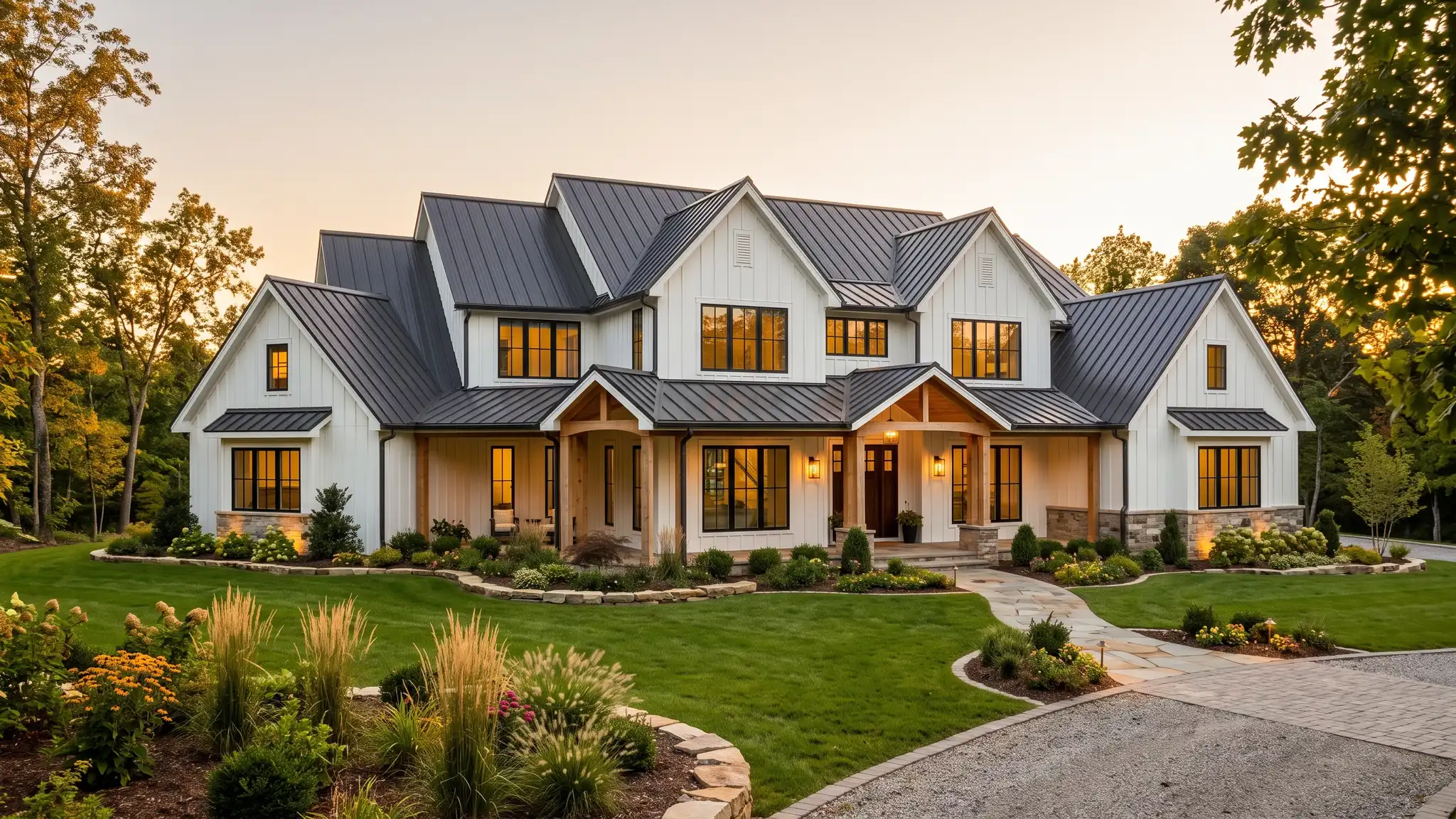 A stunning modern farmhouse custom home exterior at golden hour with board-and-batten siding, a standing seam metal roof, large black-framed windows and a landscaped lawn